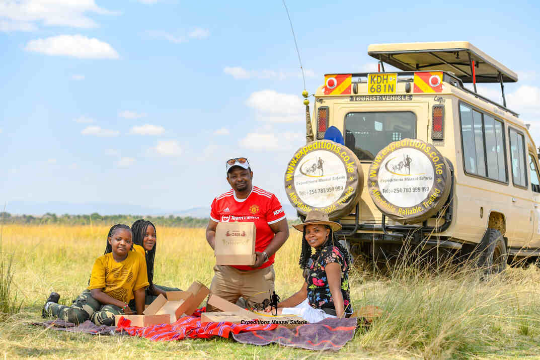A Kenyan family enjoying a picnic lunch at the Masai Mara National Reserve after a morning game drive.